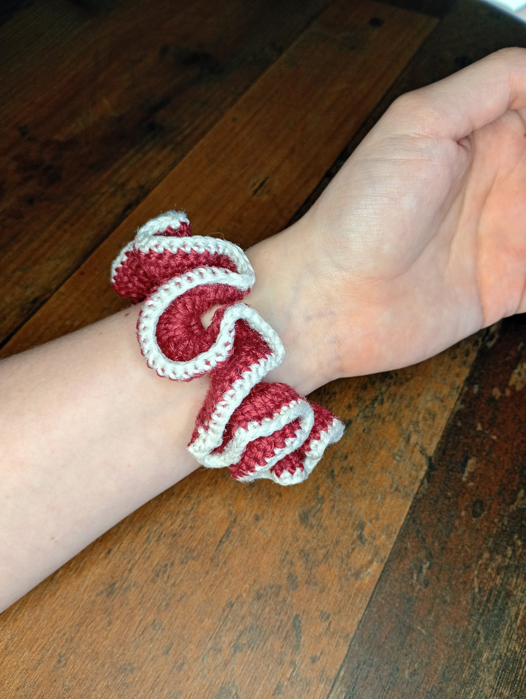 Gehäkelter Scrunchie Dunkelrot-Weiß am Handgelenk getragen