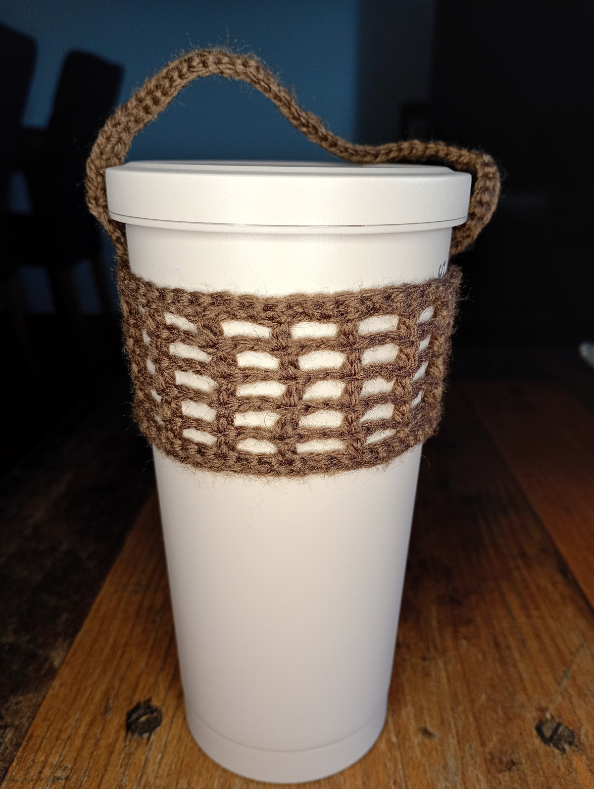 Brauner handgehäkelter Cup Cosy an einem weißen To-go-Becher