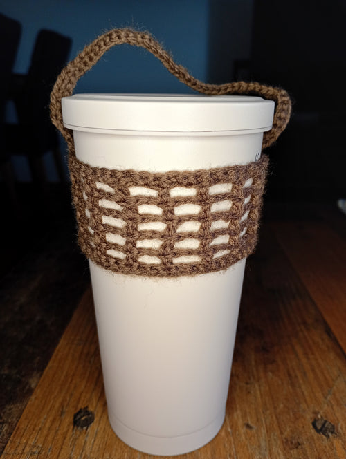 Brauner handgehäkelter Cup Cosy an einem weißen To-go-Becher